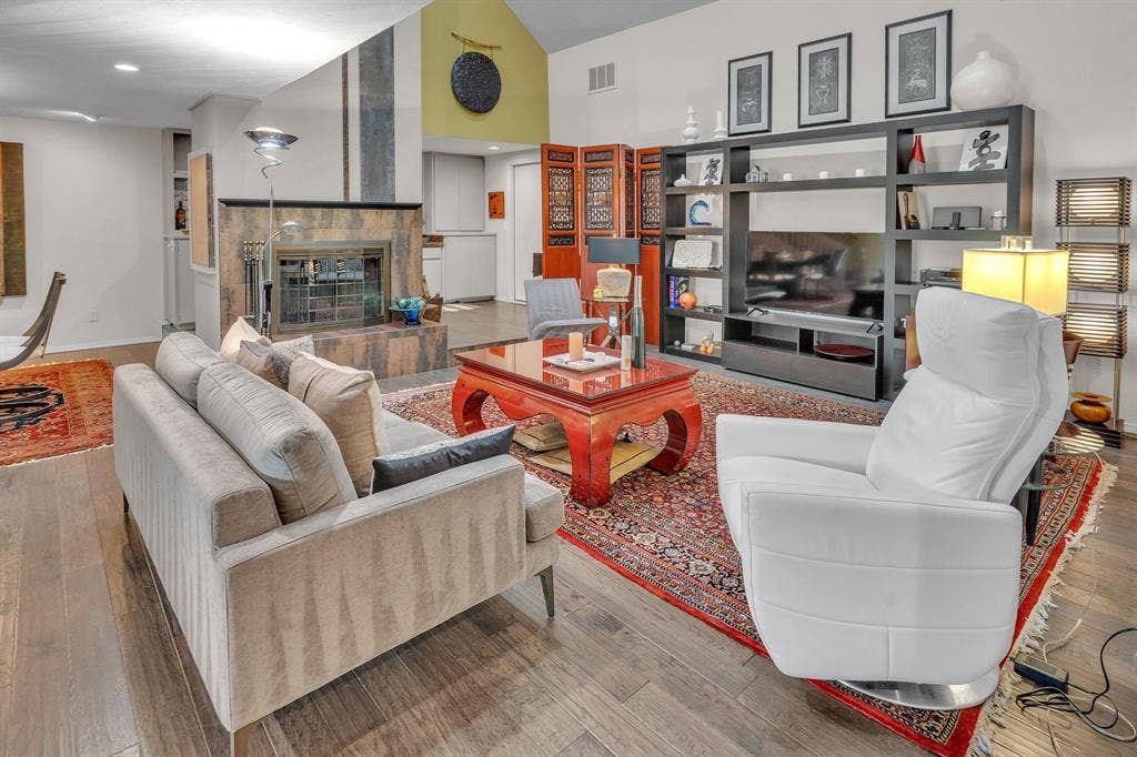 Living area with vaulted ceiling, skylight, & soaring fireplace