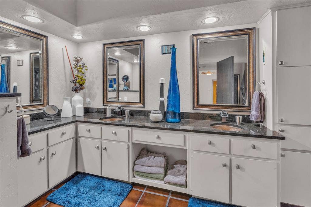Primary bathroom with double vanities, recessed lighting, & saltillo tile floor