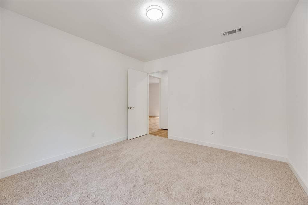 1903 Clemson Drive, Richardson, TX 75081 Wall-to-wall carpeting, bright white walls, flush mount ceiling light fixture, and a solid core door