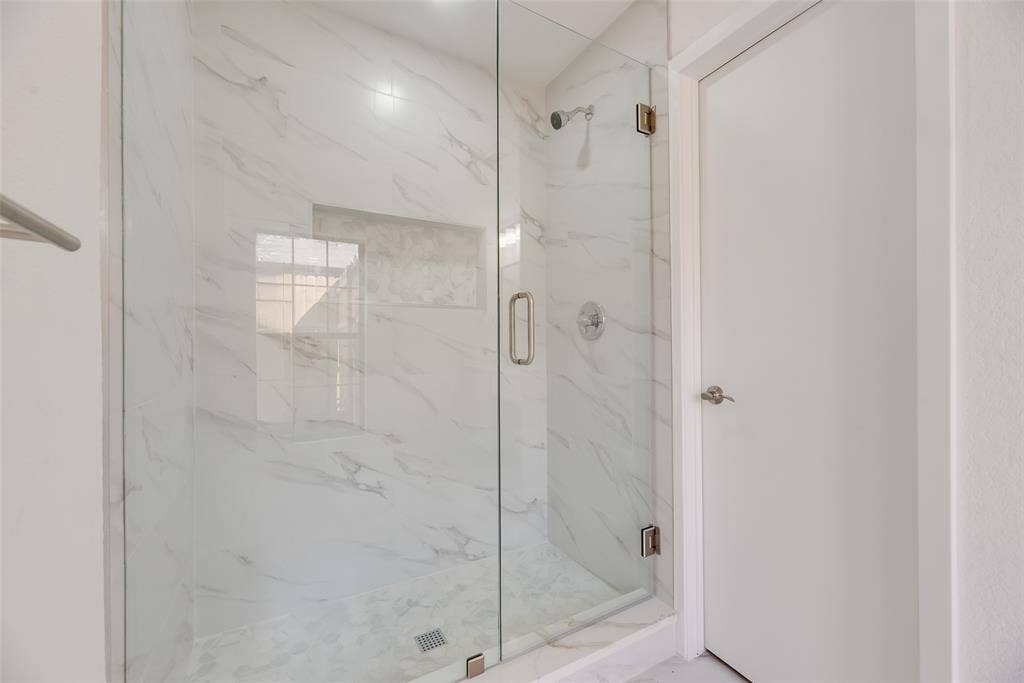 1903 Clemson Drive, Richardson, TX 75081 Glass-enclosed shower with white marble-look tile, built-in shower niche, and a contrasting shower floor
