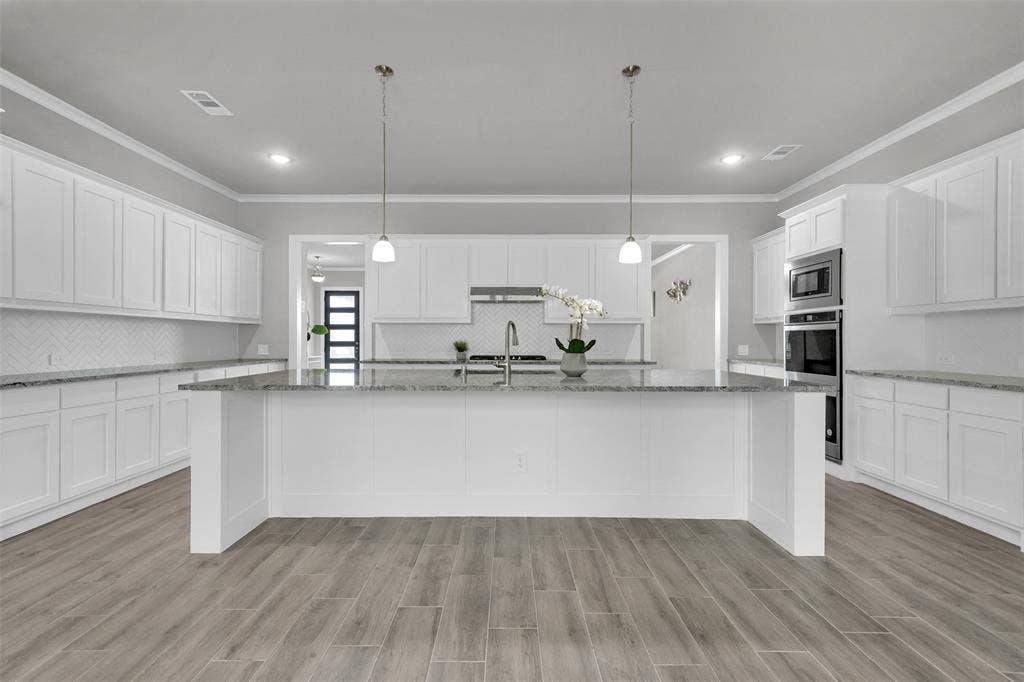 Spacious kitchen with granite countertops, double oven, large island, and custom cabinetry—ideal for entertaining
