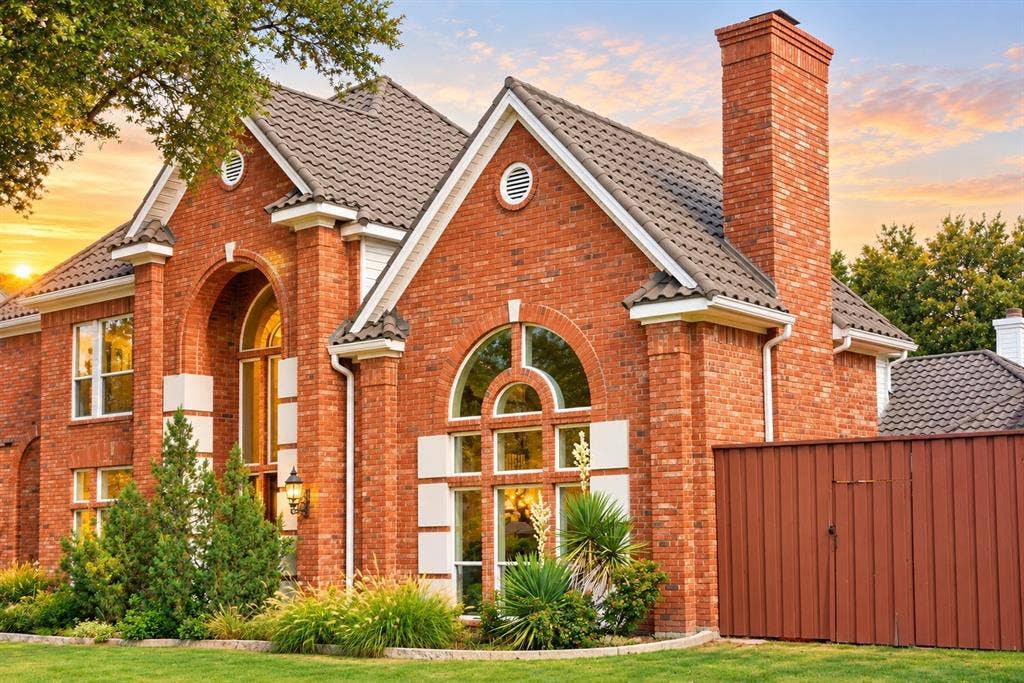 4505 Southgate Drive, Plano, TX 75024 Brick exterior featuring arched windows, a prominent brick chimney, and a tile roof