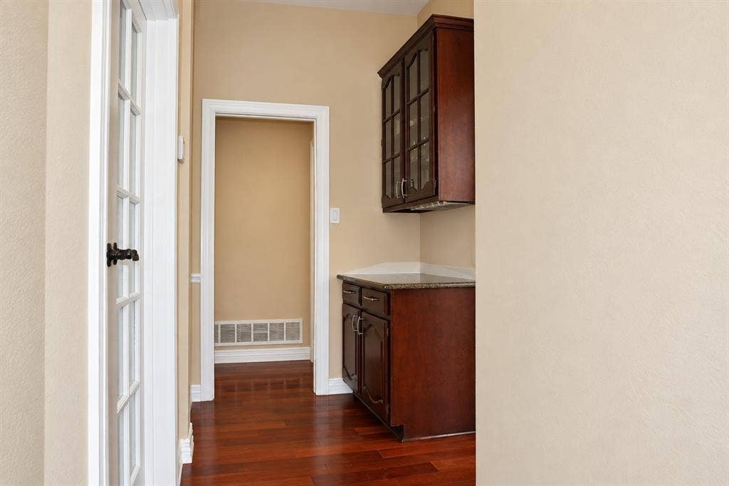 4505 Southgate Drive, Plano, TX 75024 Wood-finish flooring, dark wood cabinetry with glass door accents, and light-toned walls