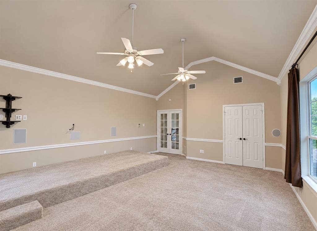 4505 Southgate Drive, Plano, TX 75024 Vaulted ceiling with crown molding, two ceiling fans, built-in wall speakers, and a carpeted stepped platform