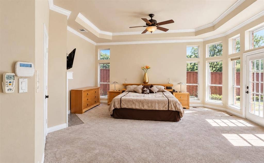 4505 Southgate Drive, Plano, TX 75024 Tray ceiling with crown molding, ceiling fan with integrated lighting, multiple tall windows, and a glass-paneled door