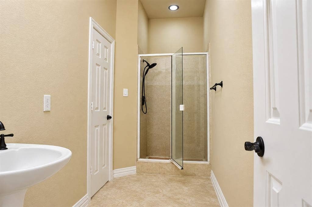 4505 Southgate Drive, Plano, TX 75024 Pedestal sink with a matte black faucet, walk-in shower with glass enclosure, recessed lighting, and tile flooring
