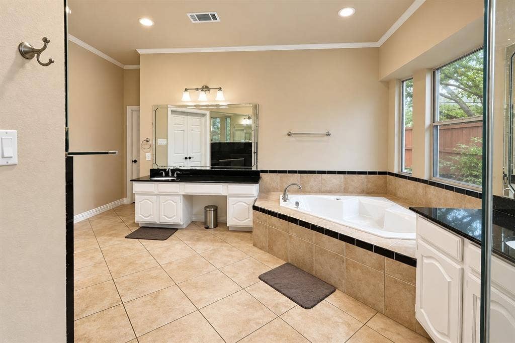 4505 Southgate Drive, Plano, TX 75024 Corner soaking tub with tiled surround, dual windows, and recessed lighting