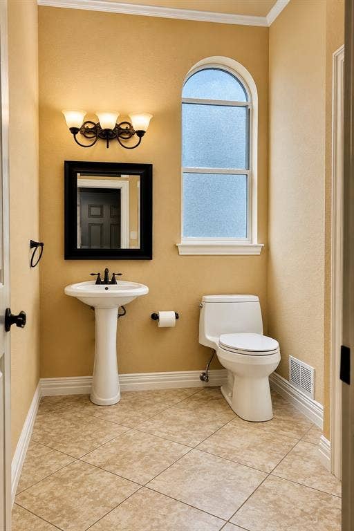 4505 Southgate Drive, Plano, TX 75024 Pedestal sink, arched frosted window, tiled flooring, wall-mounted light fixture, crown molding