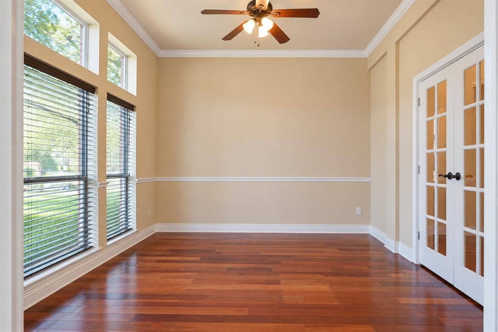 4505 Southgate Drive, Plano, TX 75024 Rich wood-finish flooring, full-light French doors, crown molding, chair rail detailing, and a ceiling fan with integrated lighting