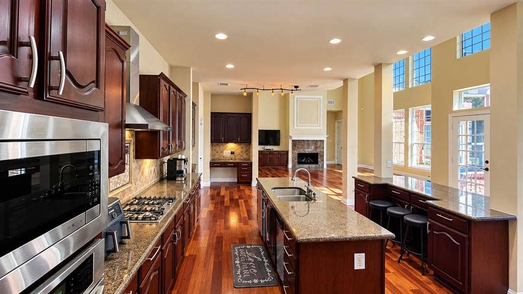 4505 Southgate Drive, Plano, TX 75024 Gourmet kitchen with rich wood cabinetry, stainless steel appliances, and a central island with a built-in sink