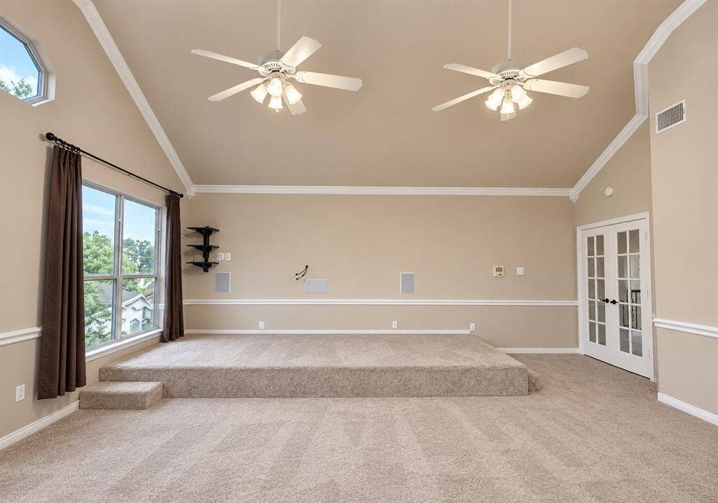 4505 Southgate Drive, Plano, TX 75024 Vaulted ceiling with dual ceiling fans, elevated carpeted platform, large windows, and French doors