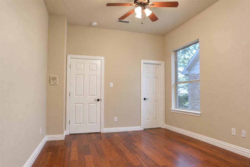 4505 Southgate Drive, Plano, TX 75024 Wood-finish flooring, ceiling fan with integrated lighting, window with white trim, two panel doors, and white baseboards
