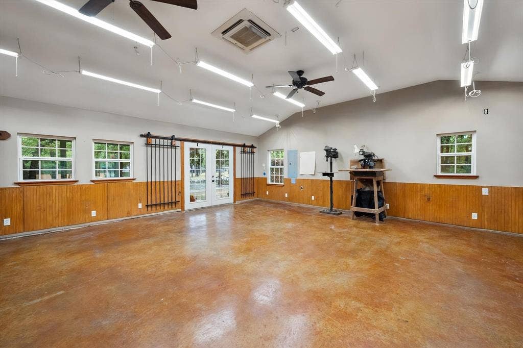 6472 Mark Drive, Burleson, TX 76028 Spacious interior featuring a concrete floor, wood panel wainscoting, and multiple windows