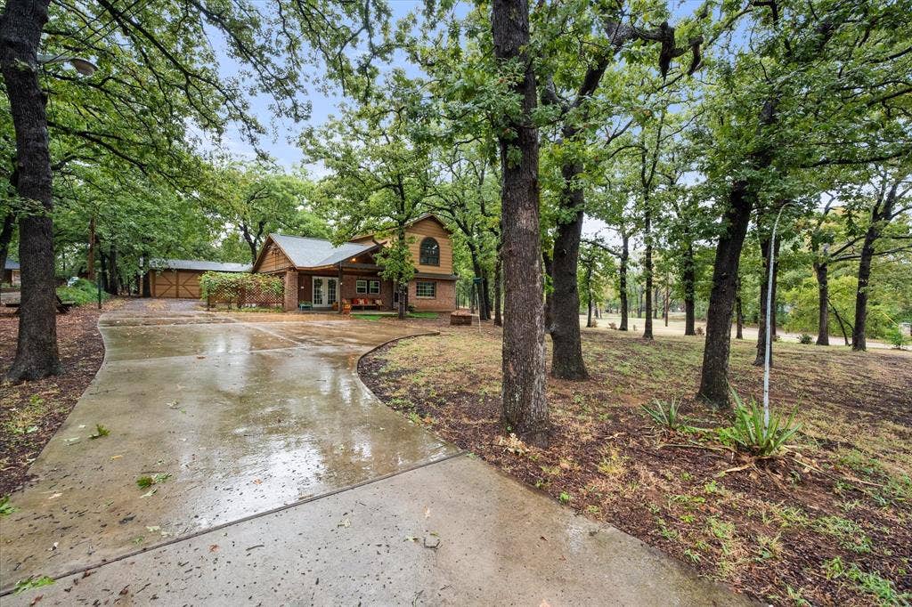 6472 Mark Drive, Burleson, TX 76028 Concrete driveway leading to a multi-level home featuring brick and wood siding