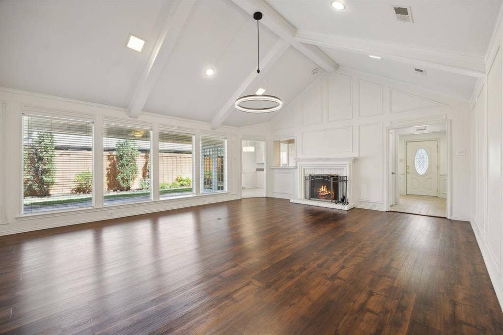 16353 Lauder Lane, Dallas, TX 75248 Vaulted ceiling with exposed beams, wood-finish flooring, white paneled walls, and a fireplace with a traditional mantel
