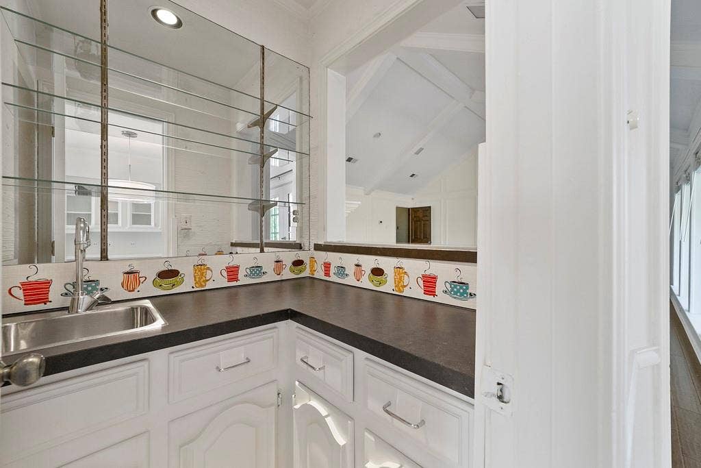 16353 Lauder Lane, Dallas, TX 75248 Built-in wet bar with a stainless steel sink, glass shelving, and white cabinetry