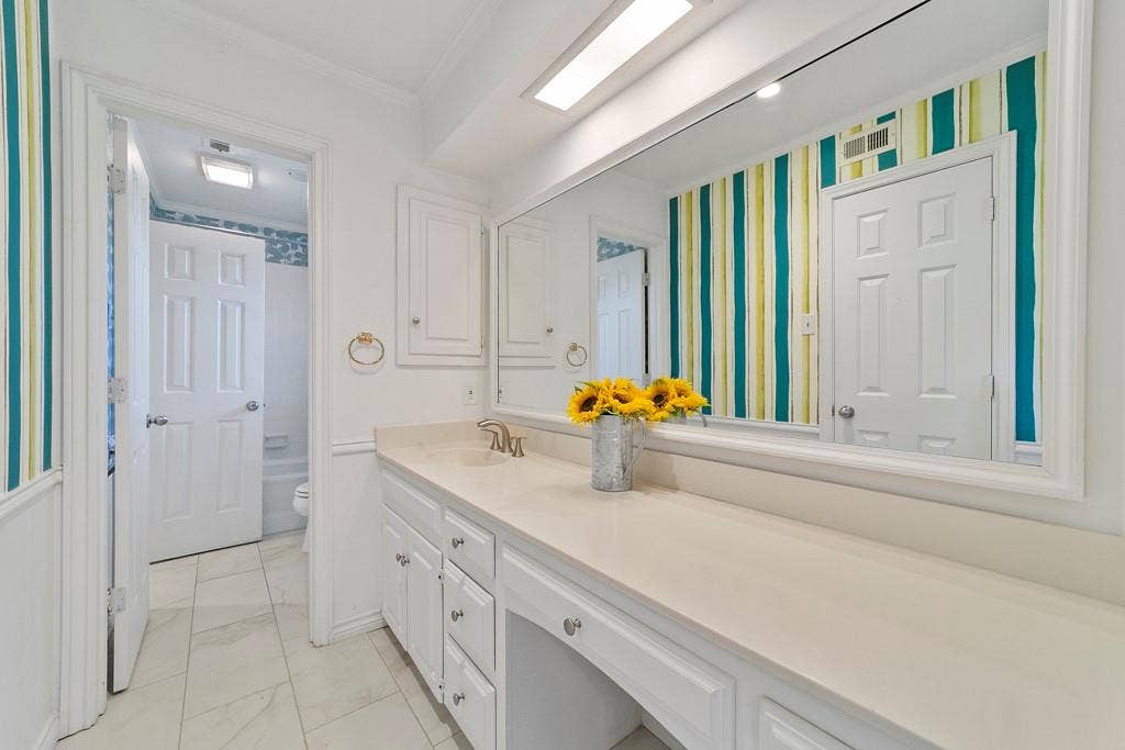 16353 Lauder Lane, Dallas, TX 75248 Extended vanity featuring a built-in dressing area, white cabinetry with silver-tone hardware, and a single basin with a chrome faucet