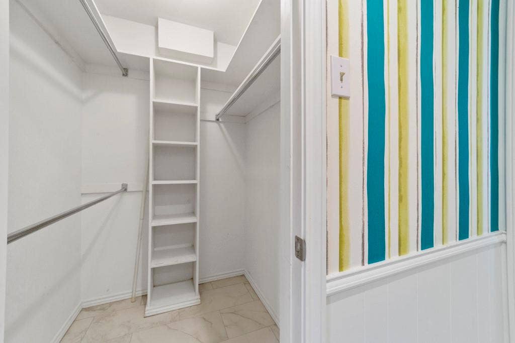 16353 Lauder Lane, Dallas, TX 75248 Walk-in closet featuring built-in shelving, dual hanging rods, and tile flooring