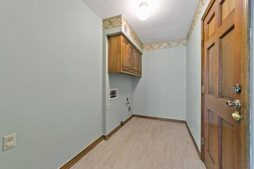 16353 Lauder Lane, Dallas, TX 75248 Wood-finish plank flooring, overhead cabinetry, and a panel-style door with metal hardware