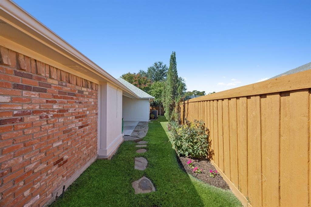 16353 Lauder Lane, Dallas, TX 75248 Manicured lawn with stepping stones, brick exterior, and a wood privacy fence