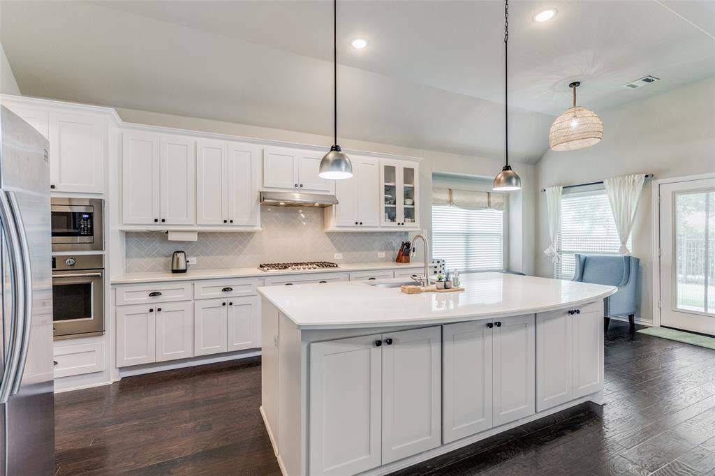 1481 Ramsbury Lane, Prosper, TX 75078 Bright kitchen featuring white cabinetry, a large center island, stainless steel appliances, and dark wood-finish flooring