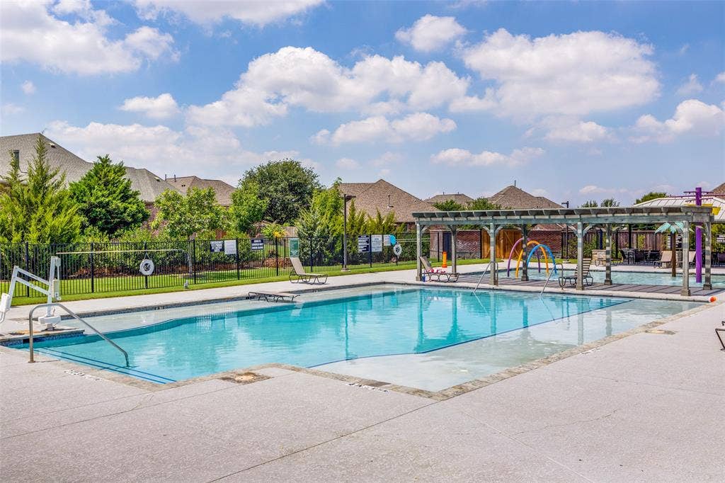 1481 Ramsbury Lane, Prosper, TX 75078 Resort-style pool with integrated splash pad, expansive concrete decking, and an adjacent shaded pergola