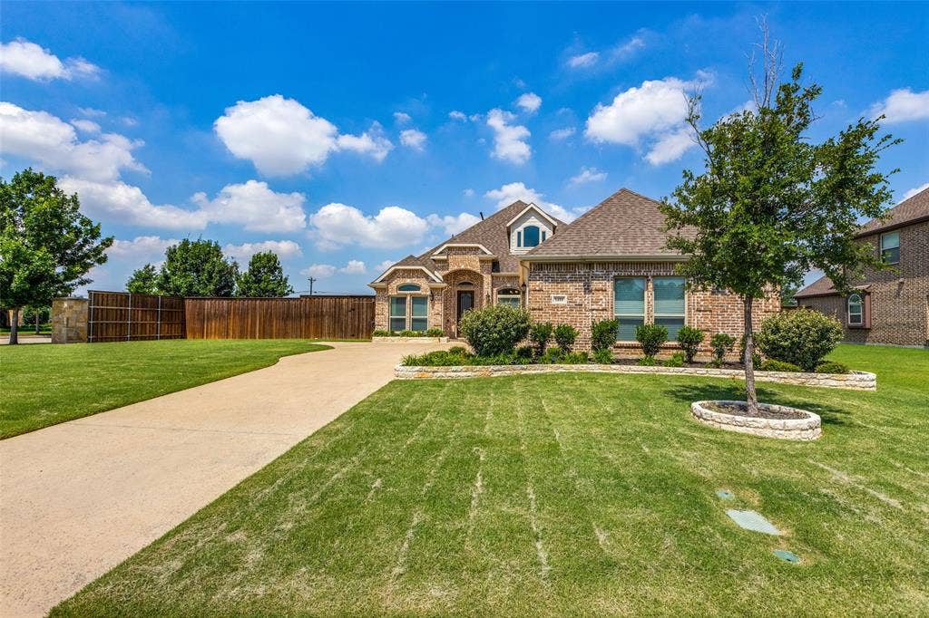 1481 Ramsbury Lane, Prosper, TX 75078 Brick exterior with stone accents, concrete driveway, front yard with green lawn, and wood privacy fence