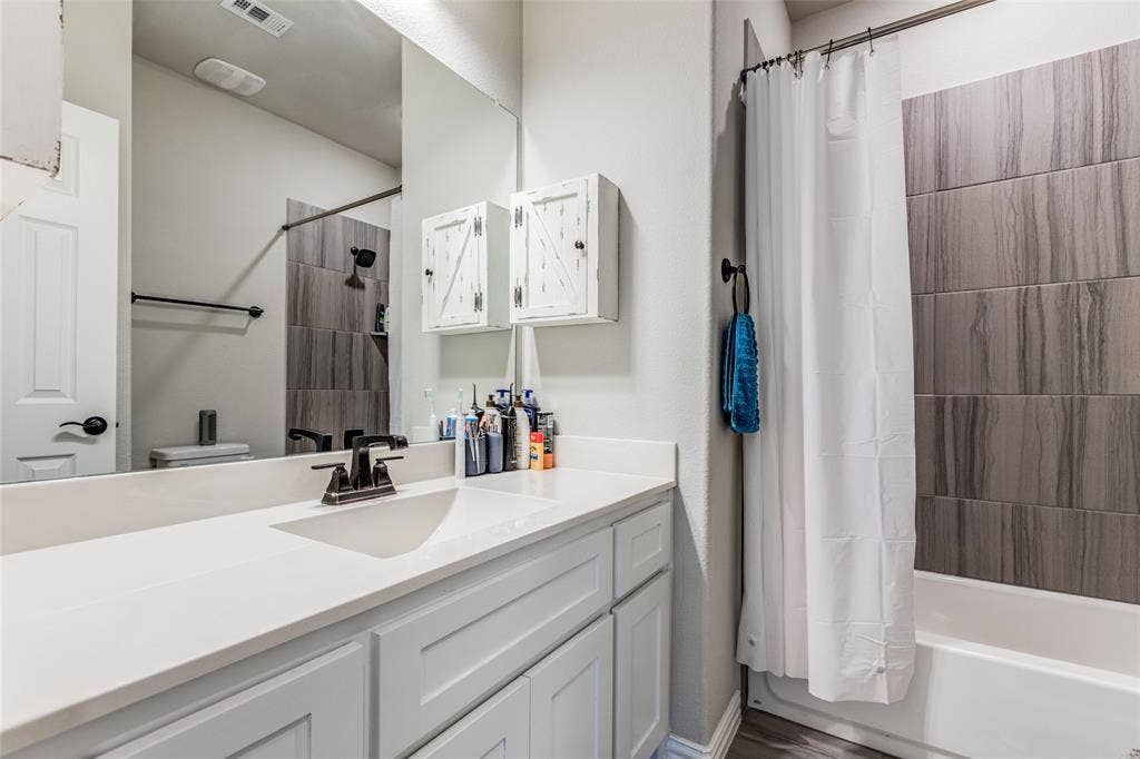 1481 Ramsbury Lane, Prosper, TX 75078 Vanity with an integrated sink and bronze-finish faucet, rectangular mirror, and white cabinetry