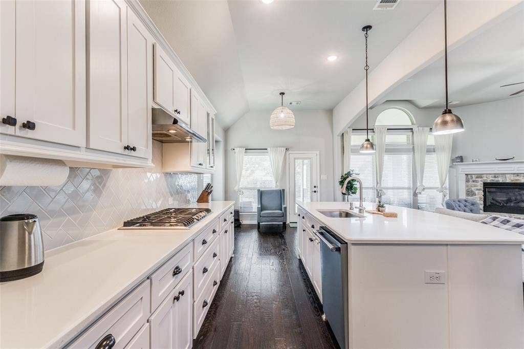 1481 Ramsbury Lane, Prosper, TX 75078 Kitchen featuring white cabinetry, light-toned countertops, a gas range, and a central island with an undermount sink