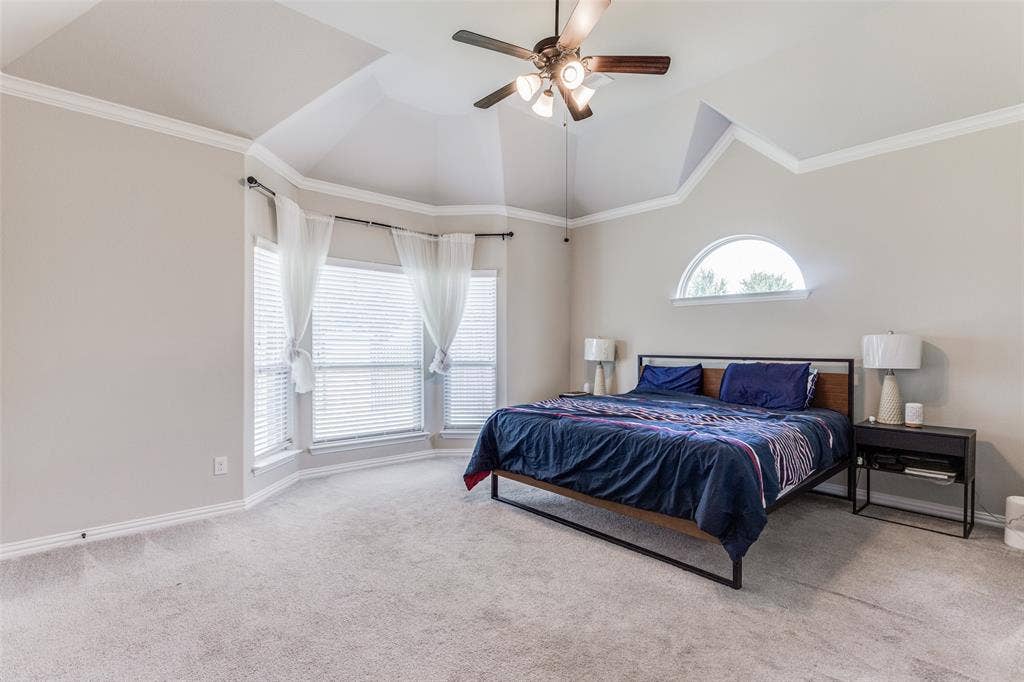 1481 Ramsbury Lane, Prosper, TX 75078 Tray ceiling with crown molding, ceiling fan with integrated lighting, bay window, arched window, and neutral wall color