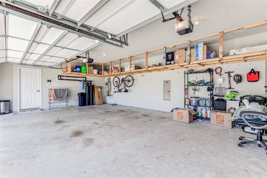 1481 Ramsbury Lane, Prosper, TX 75078 Spacious garage featuring high ceilings, overhead garage door system, built-in shelving, and direct door access