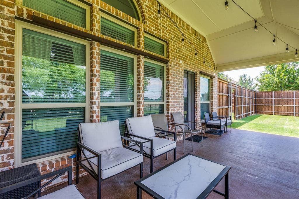 1481 Ramsbury Lane, Prosper, TX 75078 Covered patio with a stained concrete surface, brick exterior, string lighting, and a wood privacy fence