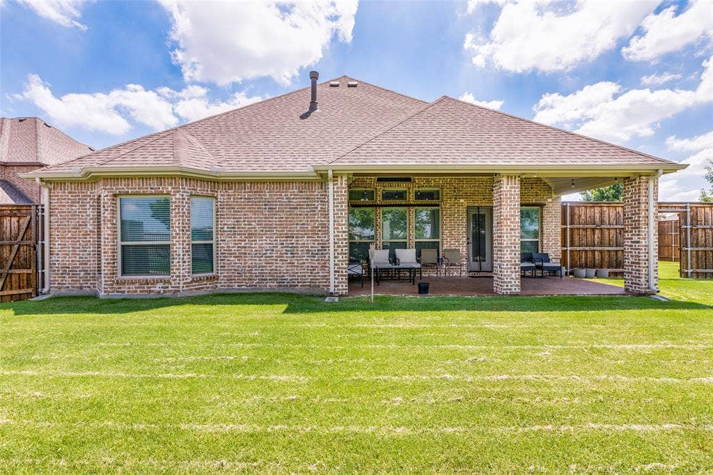 1481 Ramsbury Lane, Prosper, TX 75078 Brick exterior featuring a covered patio, multiple windows, and a shingle roof