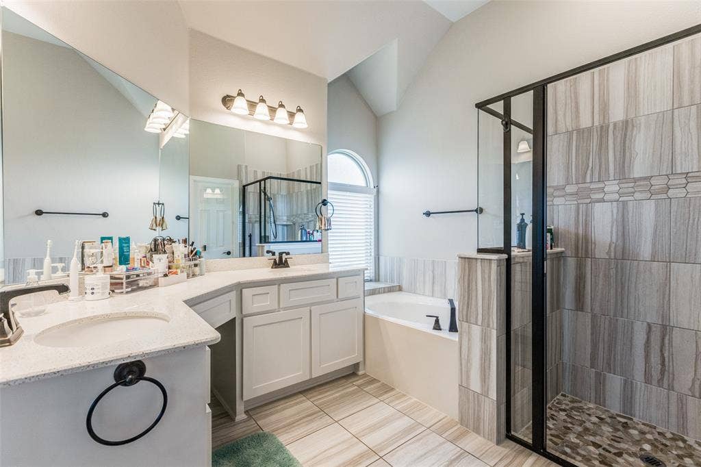 1481 Ramsbury Lane, Prosper, TX 75078 White shaker cabinetry with stone countertops, a built-in soaking tub, and a separate glass-enclosed shower featuring stone tile
