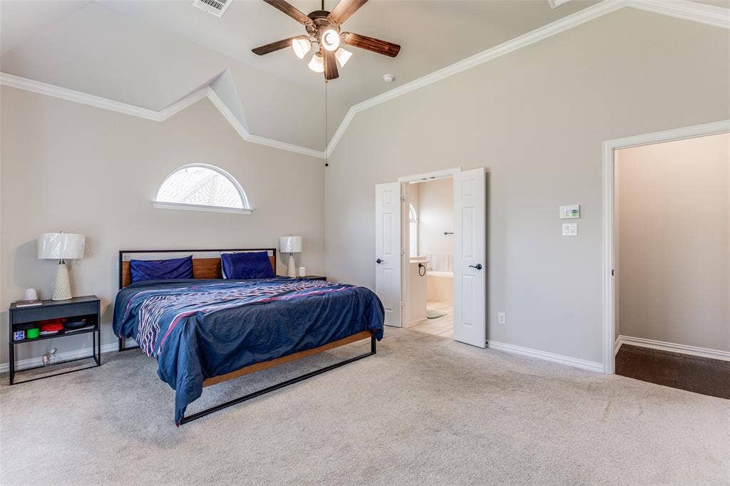 1481 Ramsbury Lane, Prosper, TX 75078 Vaulted ceiling with crown molding, ceiling fan, arched window, and carpet flooring