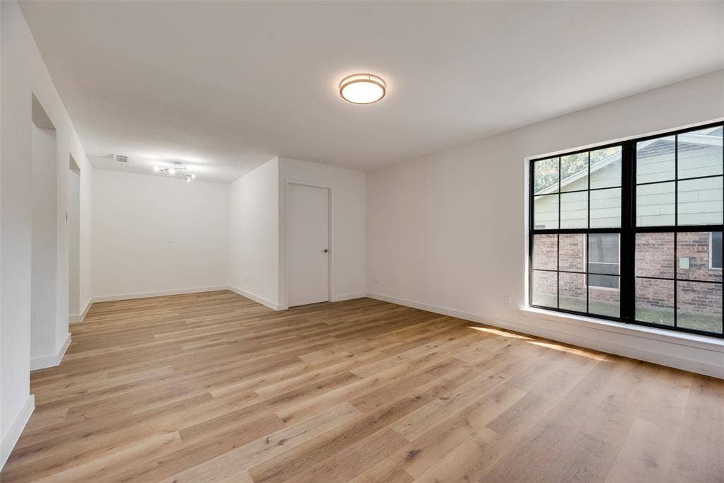 1903 Clemson Drive, Richardson, TX 75081 Light wood-finish flooring, white painted walls, and a large window with black grid framing