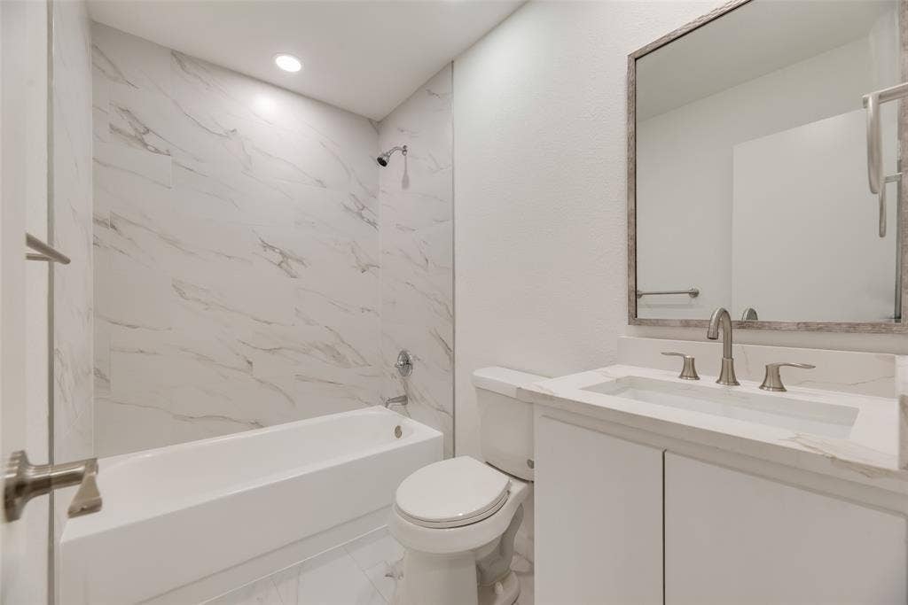 1903 Clemson Drive, Richardson, TX 75081 Bathtub with shower, white vanity cabinet with countertop, integrated sink, and framed wall mirror