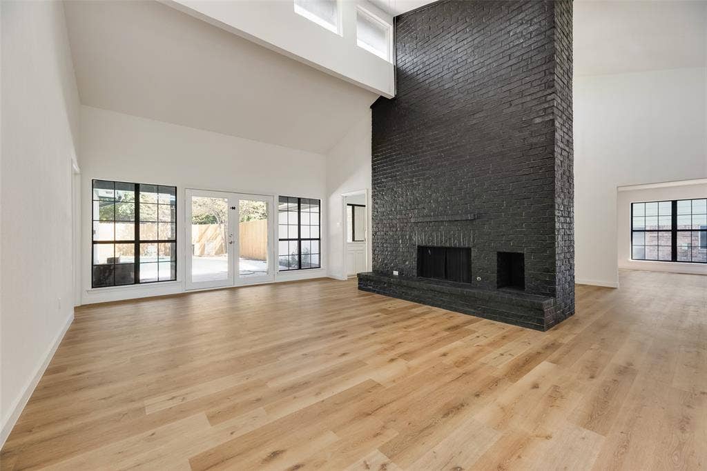 1903 Clemson Drive, Richardson, TX 75081 Vaulted ceilings, wood-finish flooring, a black brick fireplace, and large windows with black frames