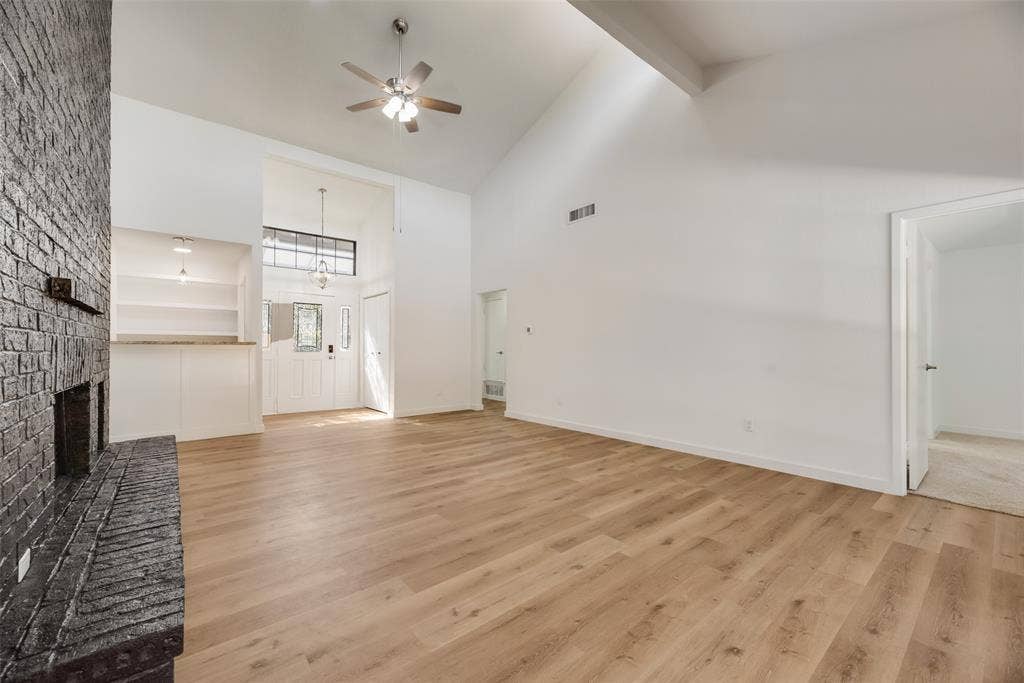 1903 Clemson Drive, Richardson, TX 75081 Vaulted ceiling featuring exposed beams, wood-finish flooring, brick fireplace, and built-in shelving