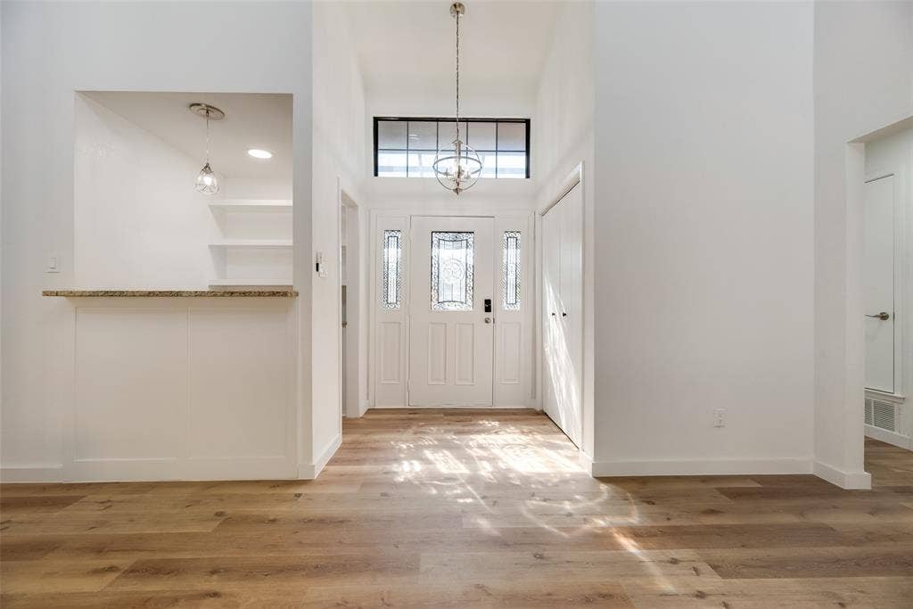 1903 Clemson Drive, Richardson, TX 75081 Wood-finish flooring, white double entry doors, transom window, vaulted ceiling, and a built-in countertop with shelving