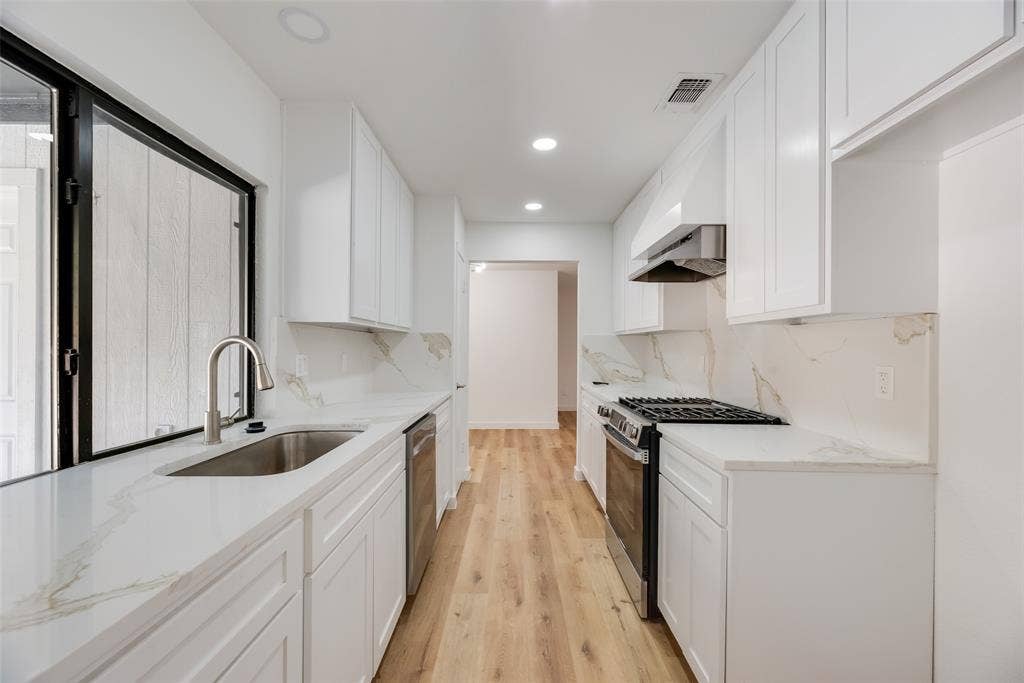 1903 Clemson Drive, Richardson, TX 75081 Galley kitchen featuring white cabinetry, light countertops, stainless steel appliances, wood-finish flooring, and recessed lighting
