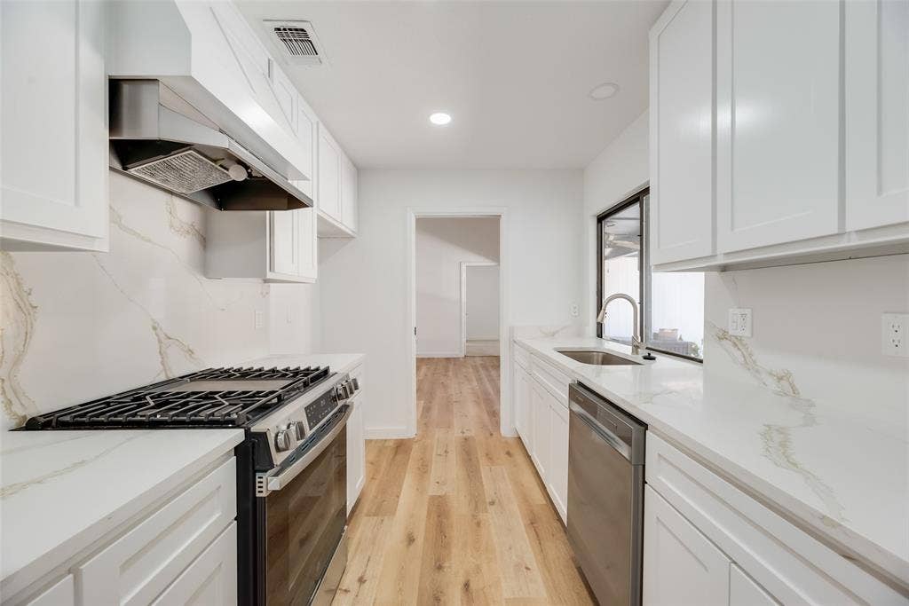 1903 Clemson Drive, Richardson, TX 75081 Galley kitchen featuring white cabinetry, quartz countertops, full-height backsplash, wood-finish flooring, and stainless steel appliances