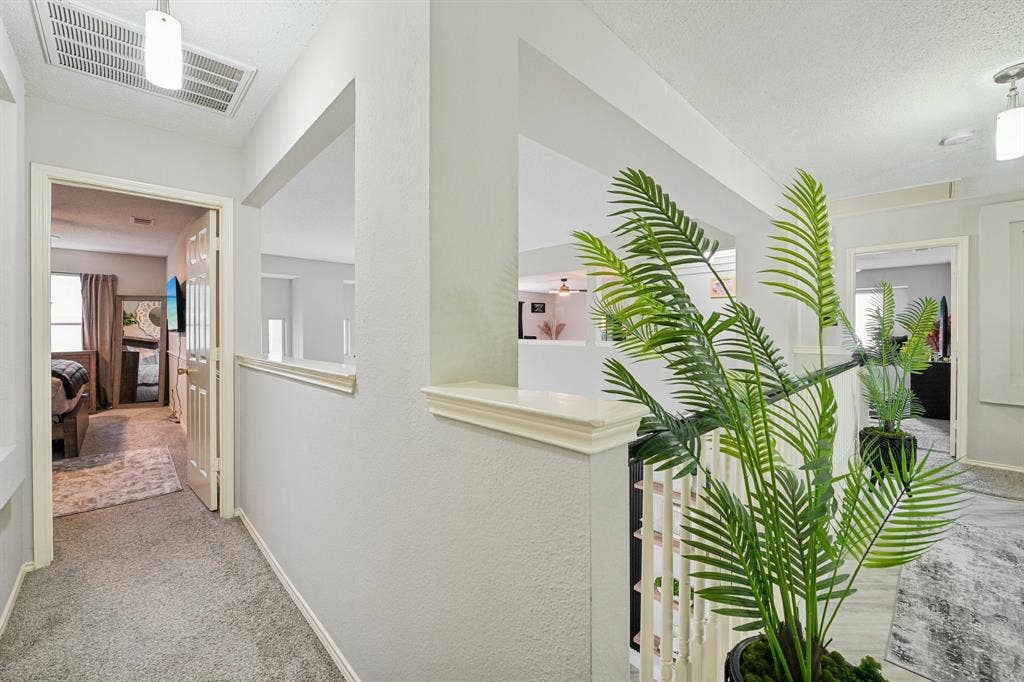 Carpeted hallway featuring a white paneled door, built-in wall shelf, and open railing