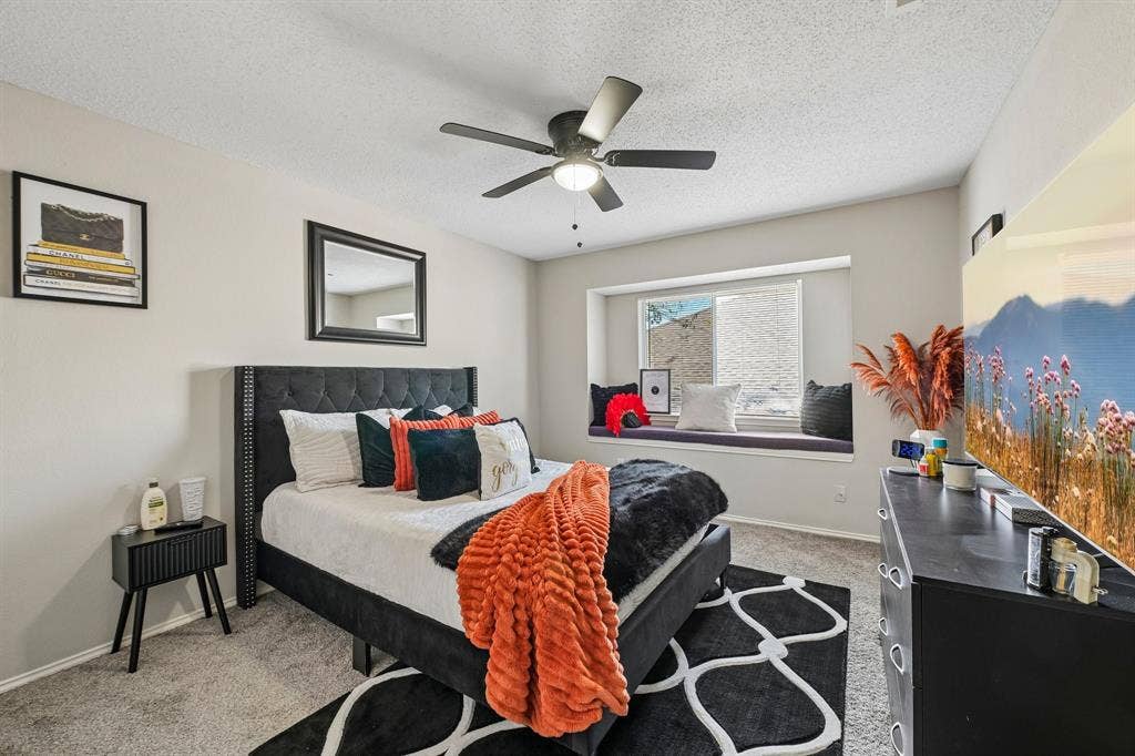 Recessed window seat, ceiling fan with integrated lighting, wall-mounted television, and carpeted flooring
