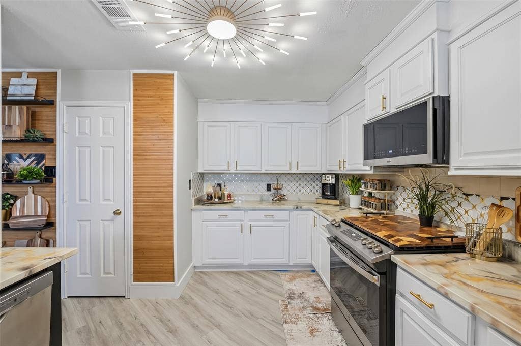 White cabinetry with gold-tone hardware, a starburst ceiling light fixture, wood-finish flooring, built-in shelving, and light-toned countertops