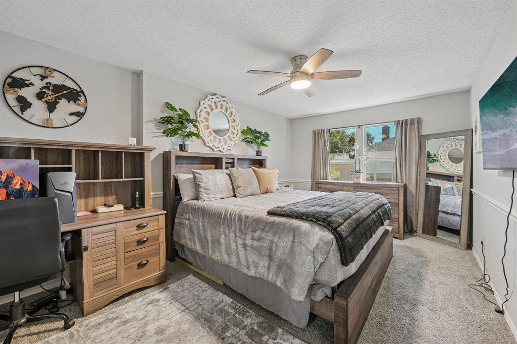 Integrated ceiling fan with lighting, carpeted flooring, window with natural light, and a built-in wall paneling detail
