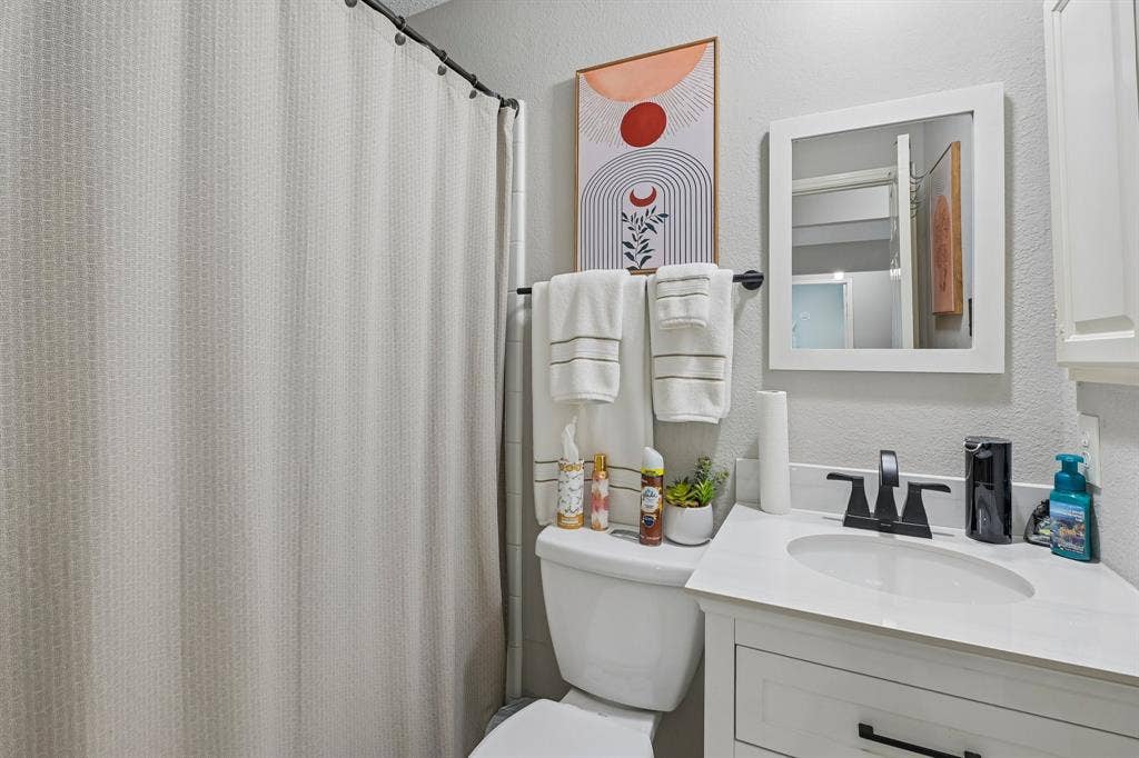 White vanity with a single basin sink, matte black faucet, and white countertop