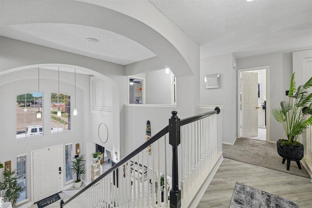 Two-story entryway with arched windows, pendant lighting, and a white paneled door