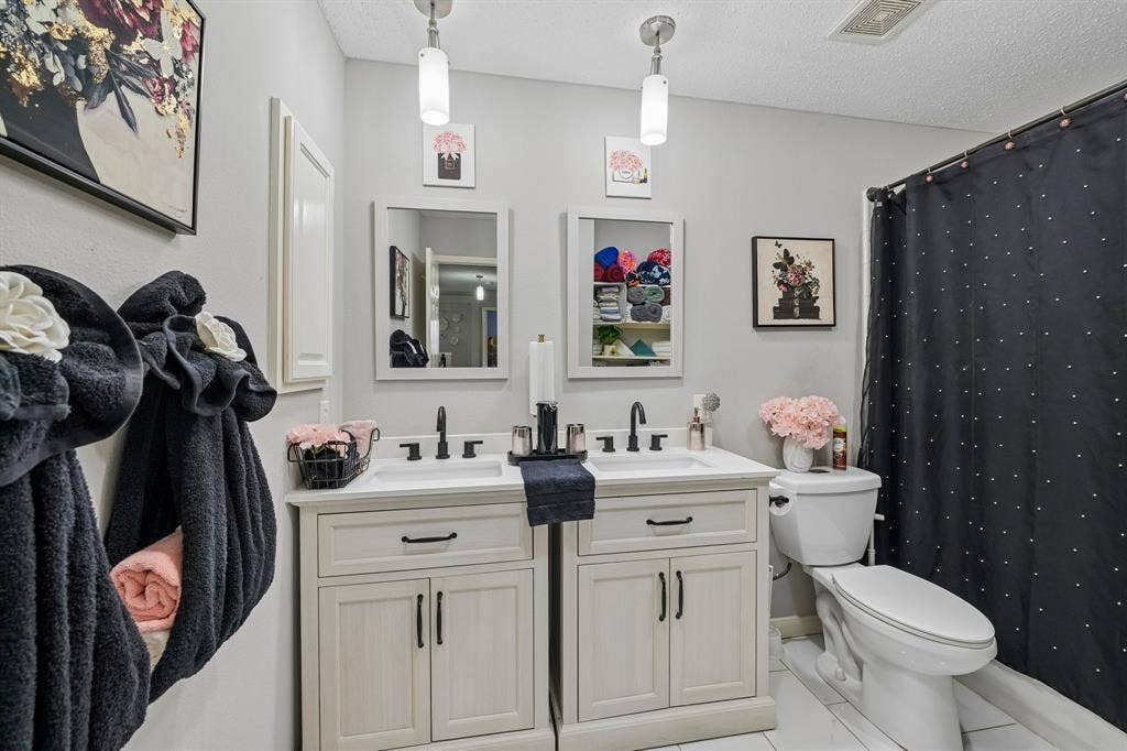 Dual single-basin vanities with matte black faucets, white countertops, and light cabinetry