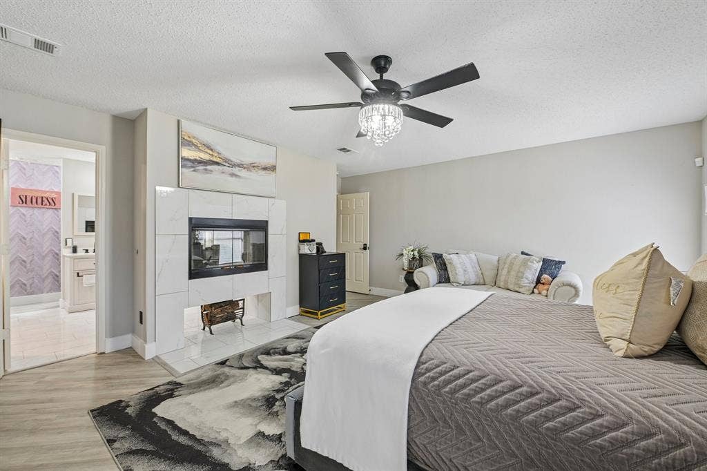Fireplace with a tile surround, wood-finish flooring, recessed lighting, and a ceiling fan with a decorative light fixture